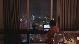 亚洲华人美丽的女人使用笔记本电脑工作，在家自习室书写耳机视频素材模板下载