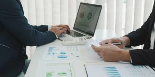 两个业务伙伴关系的同事分析成本工作进度和手势与讨论财务规划图和公司财务期间在办公室的预算会议。