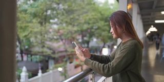 亚洲女性在城市中行走，用智能手机自拍或录像