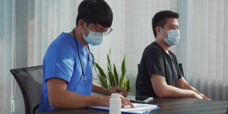 一位亚洲医生正在用听诊器听病人的心跳。