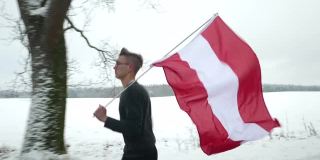 一个年轻人举着奥地利国旗在雪地里奔跑