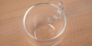 用细绳系上标签的茶袋落入一个透明的空杯子里