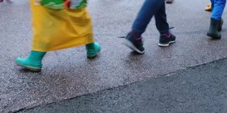 脚穿鞋走在柏油路上的孩子们在营地玩集体课活动。