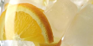 气泡饮料倒进装有橘子片和冰块的玻璃杯中，特写慢镜头