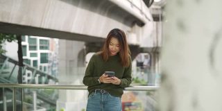 亚洲女性在城市中行走，用智能手机自拍或录像