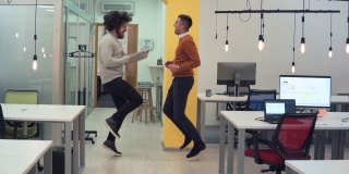 有趣的白人开发人员在办公室跳舞，庆祝他的成功。有成就后的商人欢呼——成功之道的理念