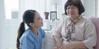 年轻的亚洲妇女或护士家微笑看着镜头与老祖母给予支持，同情老人女士或老年人在辅助生活家庭照顾心理健康疾病救济的概念。