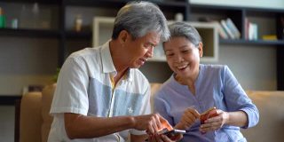 一对亚洲老年夫妇在客厅里学习使用智能手机