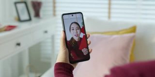 观点自拍视频通话的美丽迷人的年轻亚洲女士在红色春节庆祝服装快乐的微笑交谈和看相机手机祝农历节日。