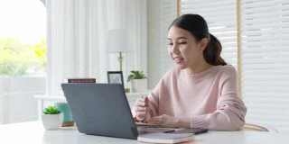 年轻有吸引力的商业亚洲女人谈论销售报告在视频电话会议上笔记本电脑在线会议在家工作，远程工作和社会隔离的概念。