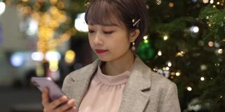 年轻的亚洲女人使用智能手机在圣诞之夜-第二部分
