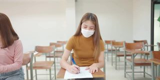 一群女学生戴着面具坐在大学教室里学习和考试，这是新常态。