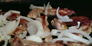 肉和洋葱一起在平底锅里炒。厨房的露天。
