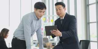 亚洲商务人士在办公室开会进行头脑风暴，亚洲经理手持平板电脑向同事展示工作计划项目，成功的商业理念，团队战略
