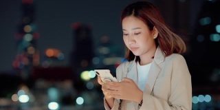 美丽的亚洲女人发短信给她的丈夫在晚上加班后的手机。