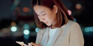 美丽的亚洲女人发短信给她的丈夫在晚上加班后的手机。