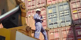 年长货务经理手持无线电控制工作过程附近集装箱货港起重机，白人男性码头工物流进出口航运概念。
