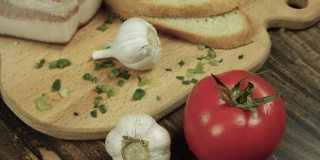 自制食物放在木托盘上，新鲜的西红柿配培根和大蒜，在厨房里烹饪。新鲜的天然产品。