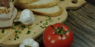 家常菜，在厨房里做菜，培根配西红柿和大蒜放在木托盘上，新鲜的食物。