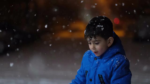 学前班的男孩晚上在雪地里玩。