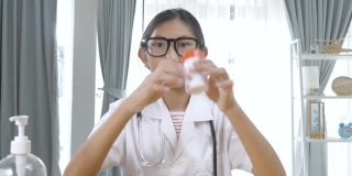 快乐的亚洲医生女孩拿着药瓶在镜头前跳舞，健康的生活理念。