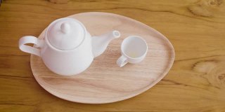 女子从茶壶倒进木桌上的茶杯中，茶道概念