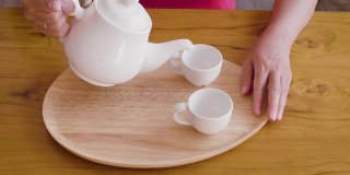 女子从茶壶倒进木桌上的茶杯中，茶道概念