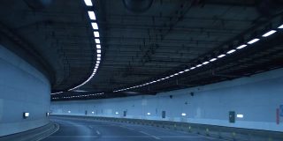 一辆车在夜间行驶在高速公路的隧道里