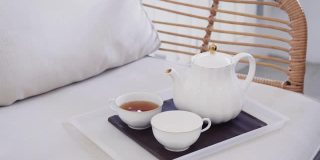 在家里的沙发上，把茶从茶壶倒进杯子里的女人，茶道概念