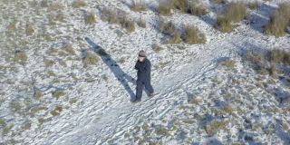 在苏格兰西南部，一位老人独自走在积雪覆盖的小路上，他在搓着双手