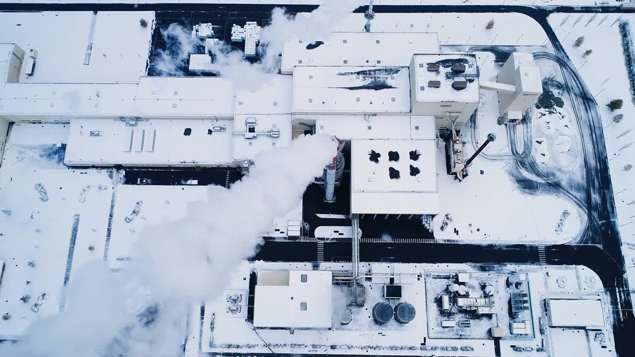 一架无人机俯瞰积雪下的工厂。我们可以看到烟从烟囱里冒出来