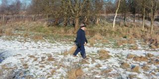 在苏格兰西南部，一位老人独自走在一条被雪覆盖的人行道上