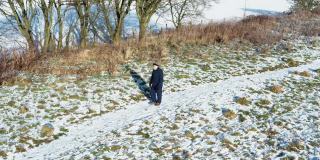 在苏格兰西南部，一名老人独自走在一条被雪覆盖的人行道上