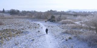 在苏格兰西南部一条被雪覆盖的小路上，一位老人独自走向摄像机的高角度镜头