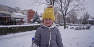 顽皮的女孩拿着一个冰铲，而有一个有趣的玩耍时间，而下雪