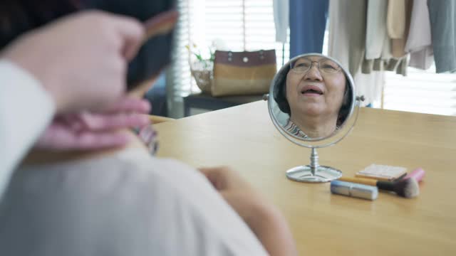 有魅力的年轻老年亚洲女性公民开心的脸在早上与护士在家例行生活方式，头发刷梳头，亚洲护理在家照顾志愿者，协助生活的服务理念。
