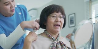 有魅力的年轻老年亚洲女性公民开心的脸在早上与护士在家例行生活方式，头发刷梳头，亚洲护理在家照顾志愿者，协助生活的服务理念。