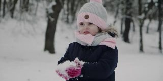 小女孩试着把手套上的雪吹掉