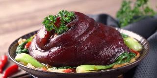 用勺子把可口的酱油倒在盘子里的台湾红烧猪腿上。
