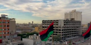 利比亚国旗飘扬在利比亚首都的黎波里上空。的黎波里的轮廓视图。