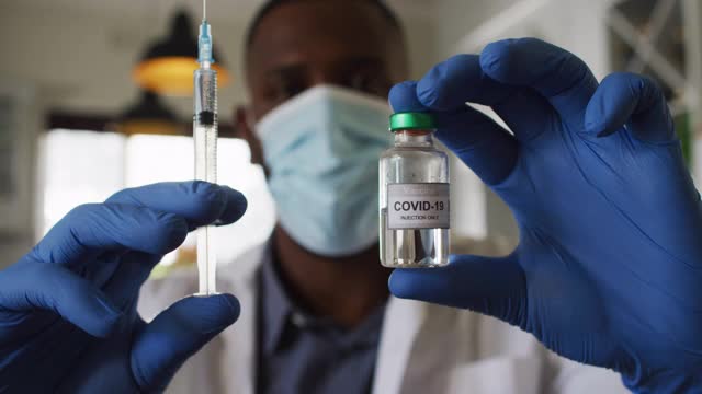 非裔美国医生戴口罩，家中携带covid-19疫苗和注射器