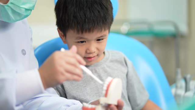 亚洲小孩在牙科诊所看牙医。牙科检查和保健的概念