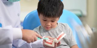 亚洲小孩在牙科诊所看牙医。牙科检查和保健的概念