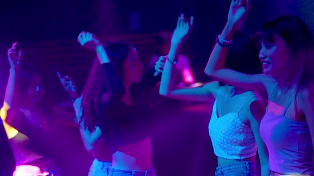 年轻人在派对音乐会俱乐部跳舞，聚会，享受夜生活。音乐表演时欢呼的人群。人们在灯光效果的地板上跳舞。