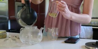 女人用松散的茶叶冲泡一杯完美的茶