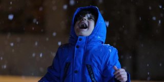学前班的男孩晚上在雪地里玩。