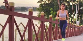 亚洲年轻健康的运动女人在公园里跑步和慢跑在锻炼期间感觉不舒服。这个女孩感到肚子痛。由于胃痛，她停止了运动。疾病和保健概念。