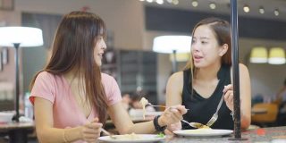 亚洲年轻的朋友，美女一起在餐厅吃饭。他们愉快地聊天，快乐地吃着食物。在自助餐厅的年轻人聚会。