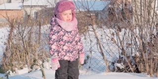 寒假，假期，游戏，家庭概念-中部计划正宗的幼稚园小女孩3-4岁在紫色的草地上走在下雪的乡间小路上。孩子在雪地上奔跑