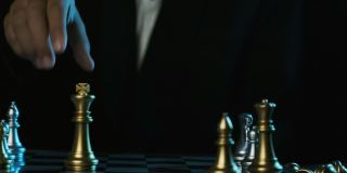 近距离的商人手移动白色皇后棋子在棋盘上孤立的黑色背景。下象棋的人。